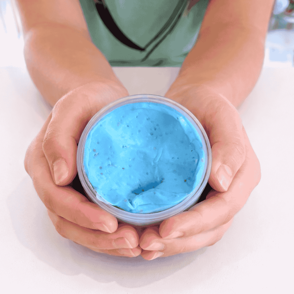 Picture of a hand Holding An Open Container of the Scented Kreamy Putty