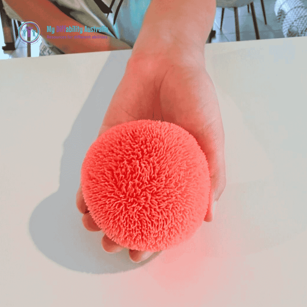 Picture of hand holding in ones palm the NeeDoh Fuzz Ball