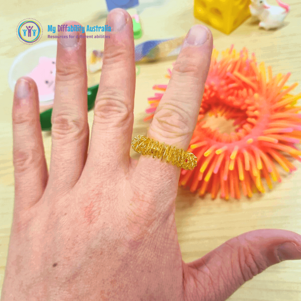 Spikey Ring a Fidget Worn In a persons finger with other fidgets in the background