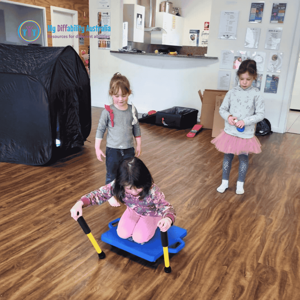 Young Girl Riding Scooter Board Large While 2 Kids Are Watching