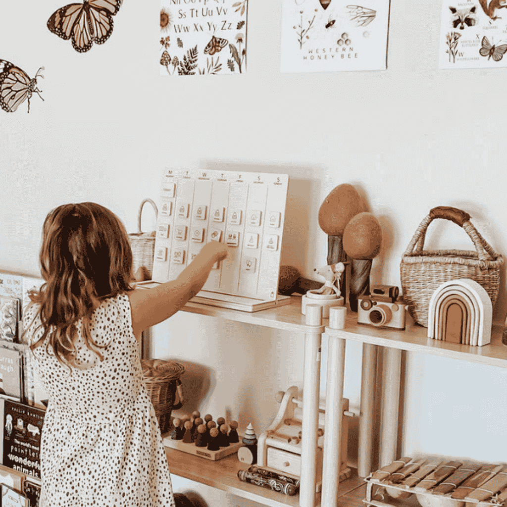 Young Girl Standing While Arranging the tiles of Little Agenda Wooden Weekly Visual Schedule