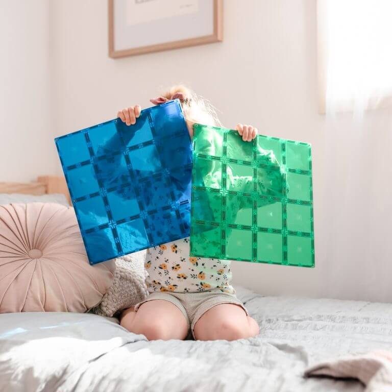child holding 2 piece magnetic tile blue green