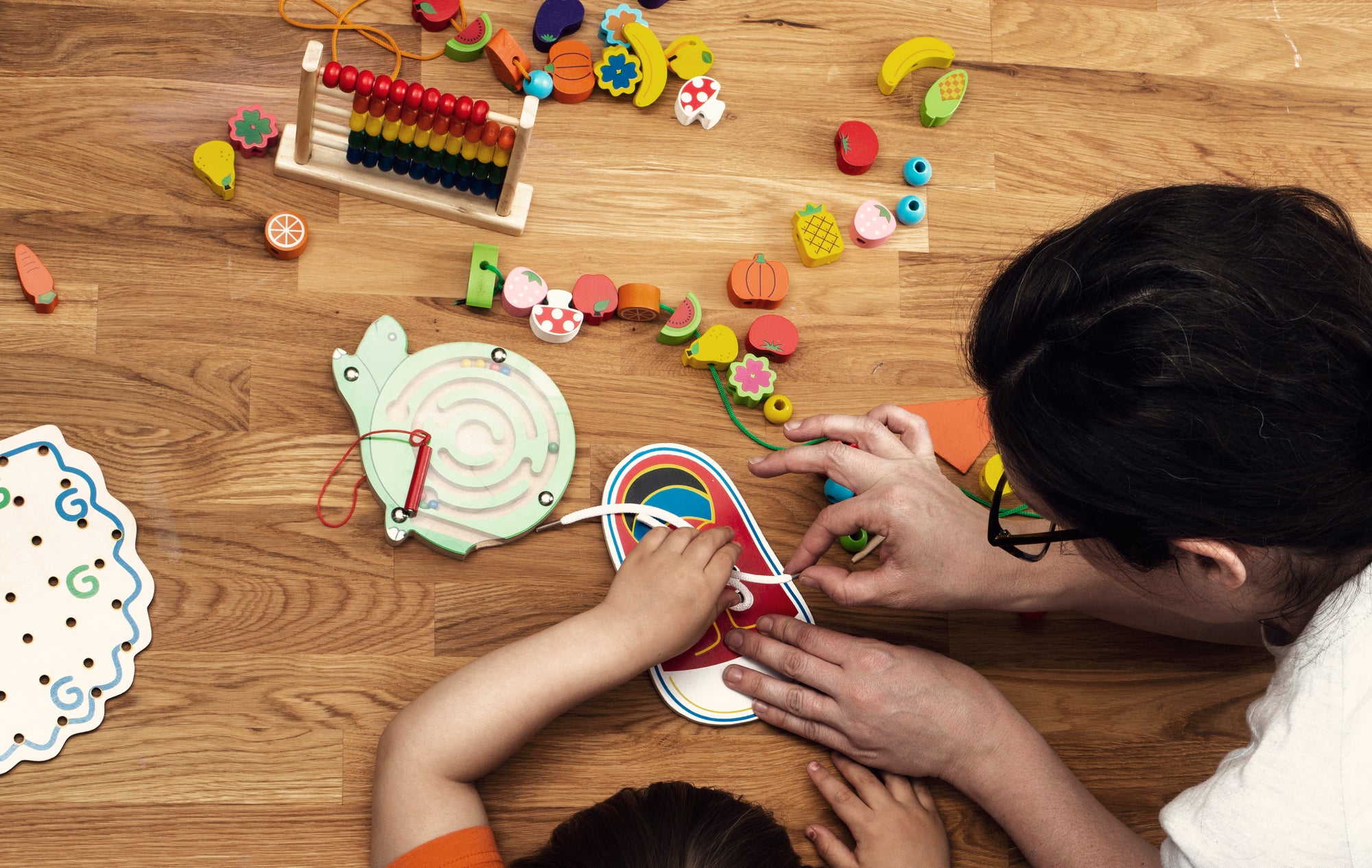 adult helping a child tie shoe laces
