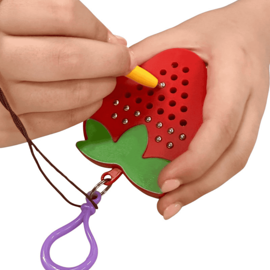 Hand playing playing Strawberry Magnetic Pad Keyring