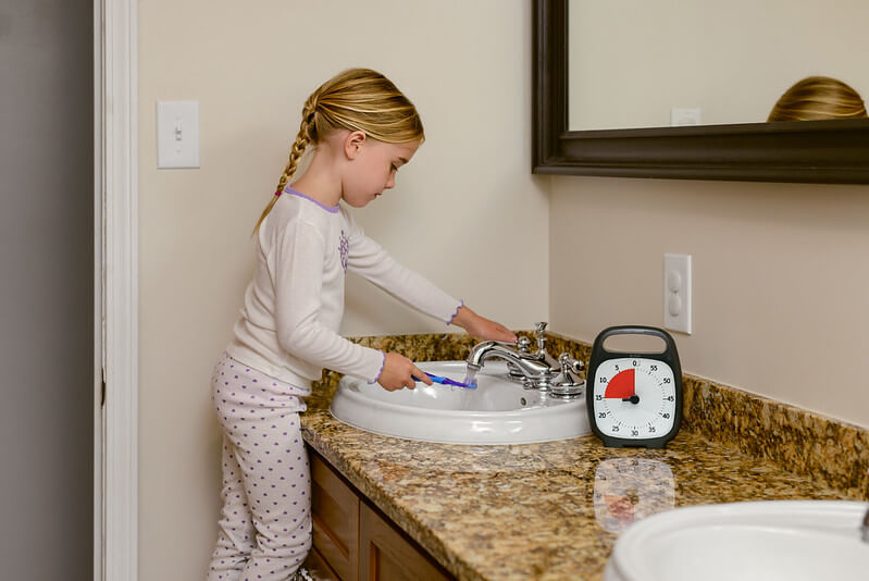 kid brushing her teeth while using time timer plus 60 minute with pause feature