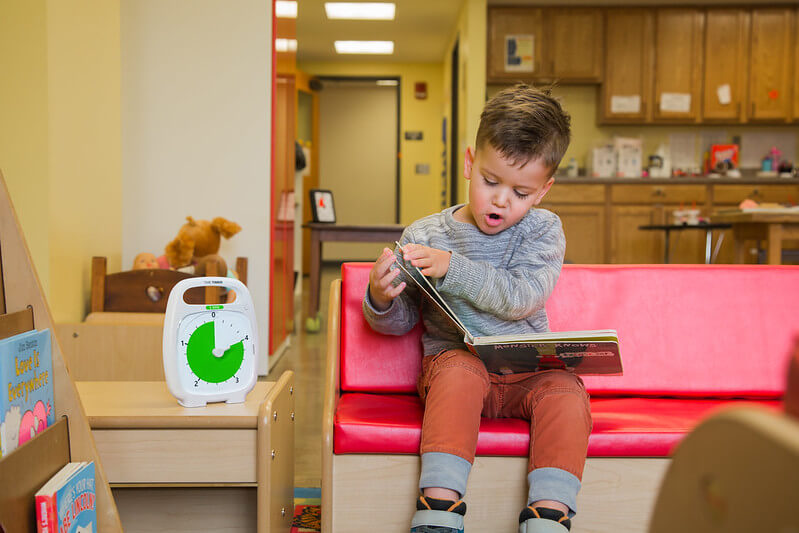 kid reading book while using time timer plus 5 minute with pause feature