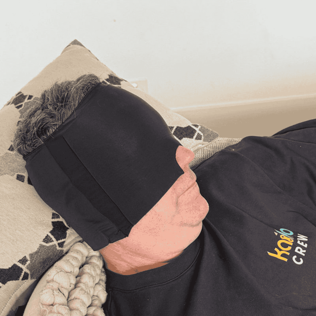 Person laying on the couch wearing Block Out Cooling Head Mask