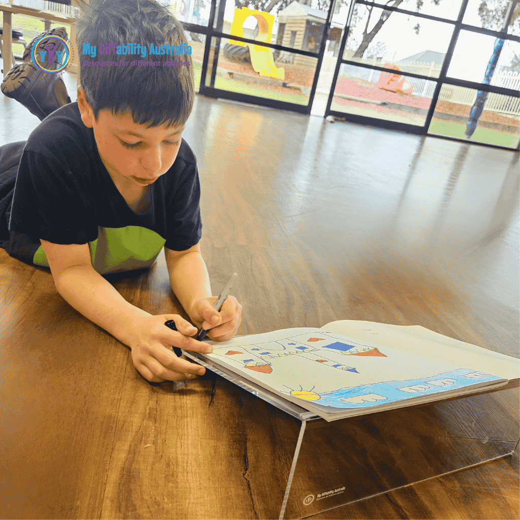 young boy laying on the floor using the slant board for drawing