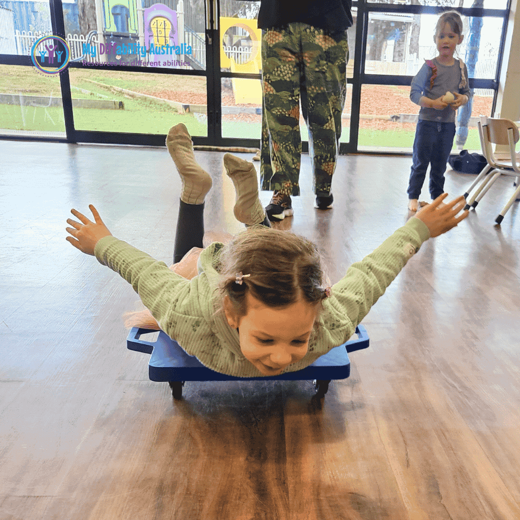 young child lying face down on blue scooter board