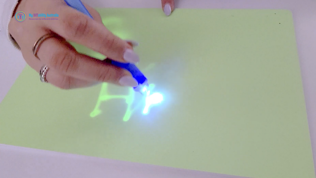 Person writing with the UV invisible spy pen on a Light up drawing board