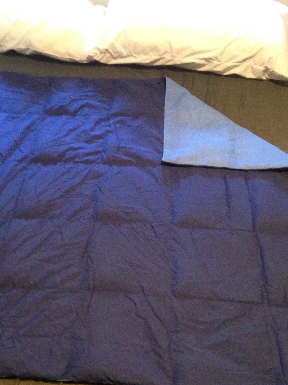 navy blue and light blue weighted blanket shown on a bed with white pillows