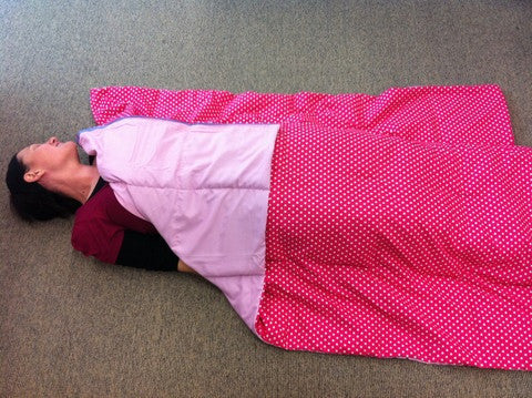 Person lying on the ground covered with pink double weighted blanket